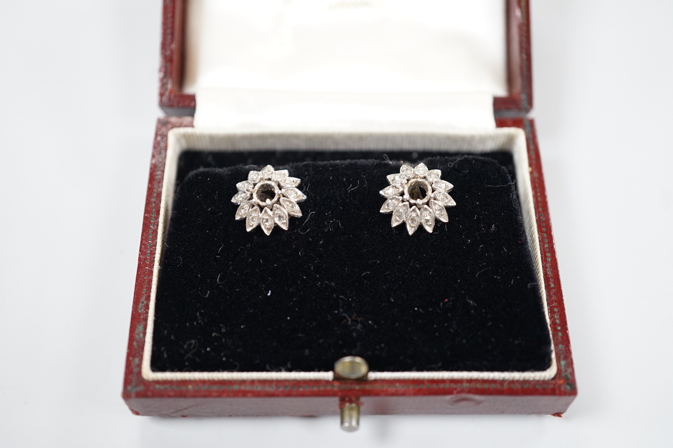 A cased pair of white metal and diamond cluster set flower head ear studs, both lacking centre stone, diameter 13mm, gross weight 4.4 grams.